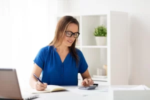 Woman With Calculator And Notebook At Office