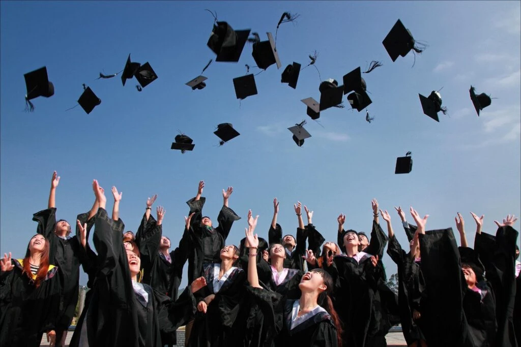 Newly Graduated People Wearing Black Academy Gowns Throwing Hats Up In The Air 1024X683 1