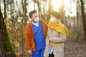 Certified Nursing Assistant Walking With An Elderly Woman In A Park