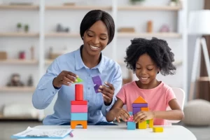 Friendly Female Teacher Playing With Little Girl