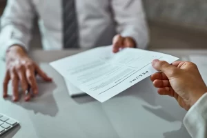 Close Up Of A Candidate Handing Their Resume During Job Interview