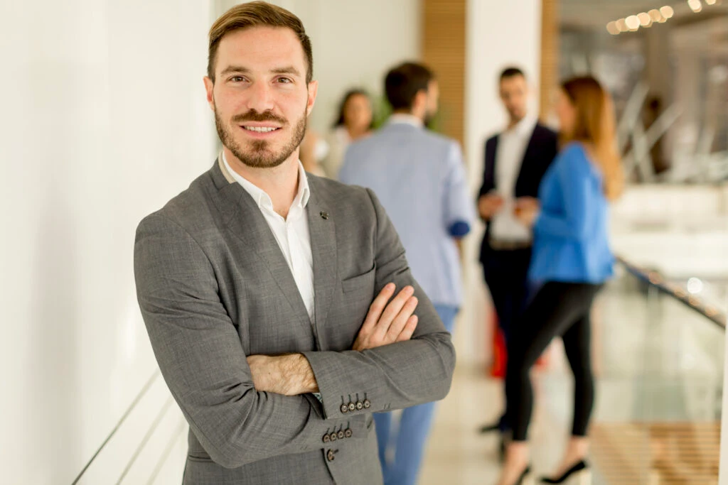 Ceo Posing While His Employees Are Discussing In The Background 1024X683 1