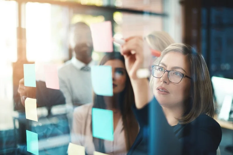 A Focused Professional Reviewing A Strategic Business Plan On A Conference Room Board