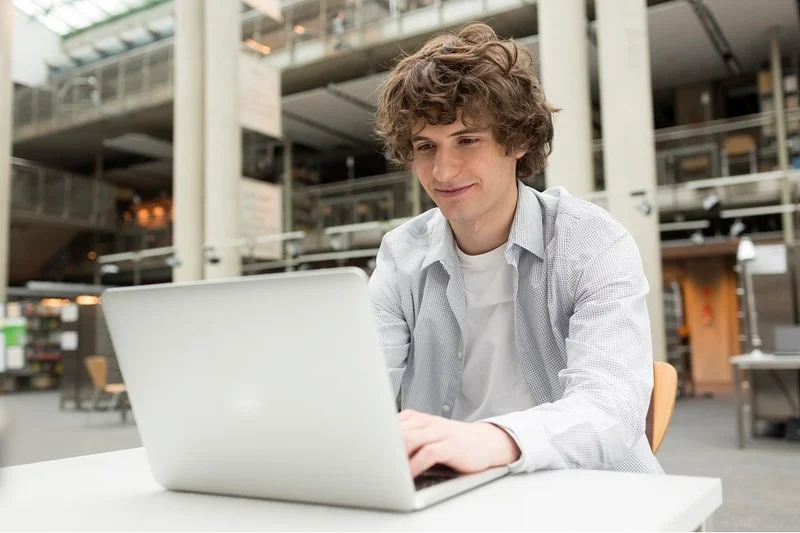 A Job Seeker Using A Laptop To Research Hybrid Workplace Strategies