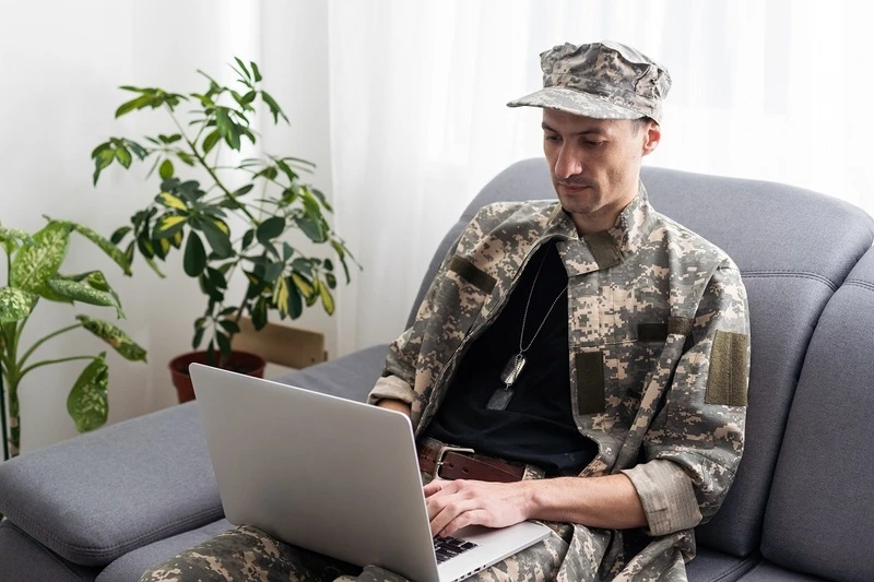 A Soldier Writing A Military To Civilian Resume On A Laptop