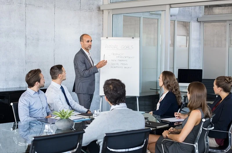 A Team Leader Demonstrating Exceptional Business Acumen During A Meeting With Colleagues