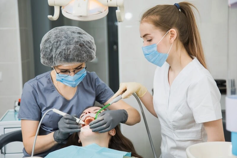 Dental Assistant And Dentist Performing A Treatment On A Patient