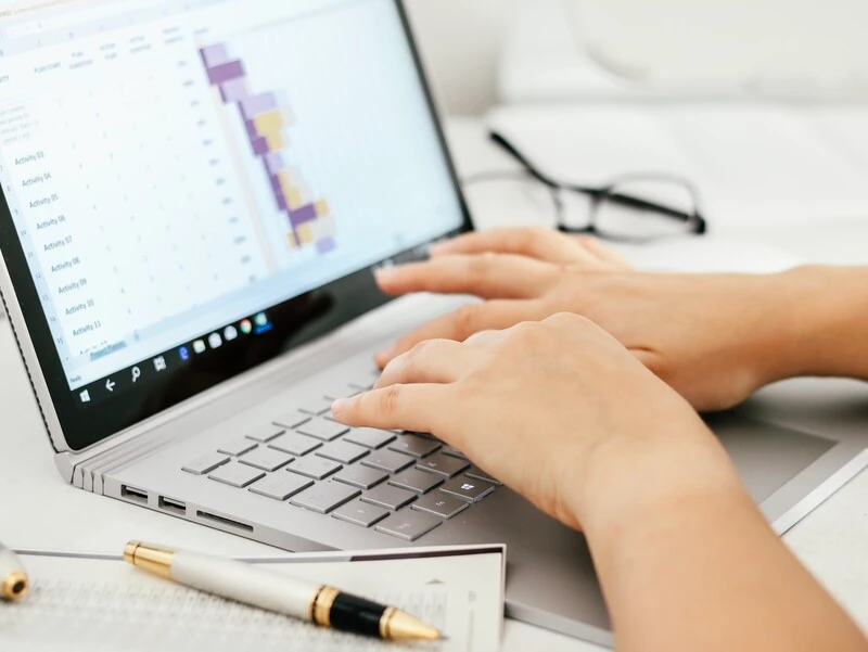 Finance Analyst Typing Financial Data On Laptop