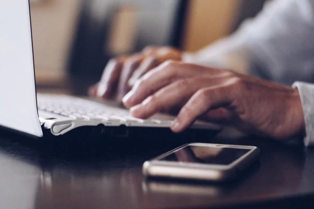 Man Using His Laptop To Browse For Fundraising Manager Resume Example Online