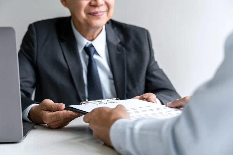 Senior Committee Manager Reading A Resume During A Job Interview E1647244895343