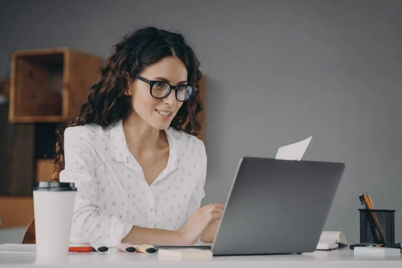 Woman In Glasses Working On Laptop From Home E1647579608298