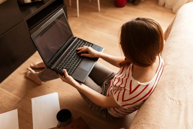 Young Woman Job Seeker Using Her Mobile Phone While Working With Laptop E1653293076480