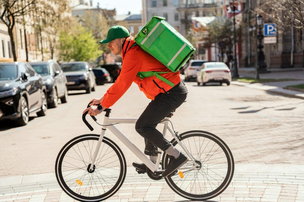 Delivery Cyclist With Green Insulated Backpack In The Gig Economy