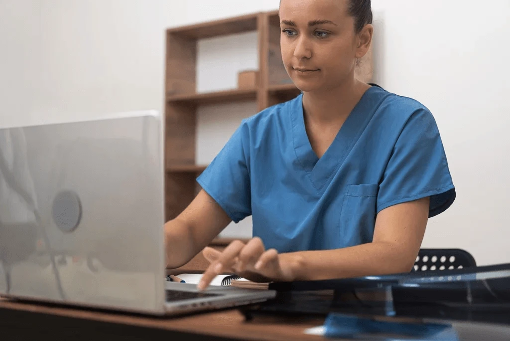 Medical Assistant Updating Her Resume Using A Laptop