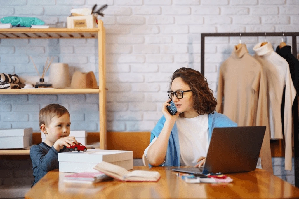 Mother Exploring Profitable Home-Based Business Ideas With Her Son Playing Beside