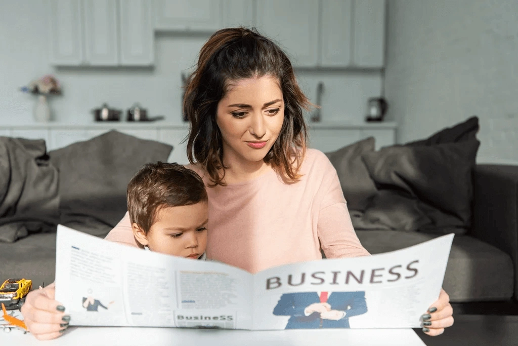 Mother Reading About Home Business Ideas While Taking Care Of Her Son