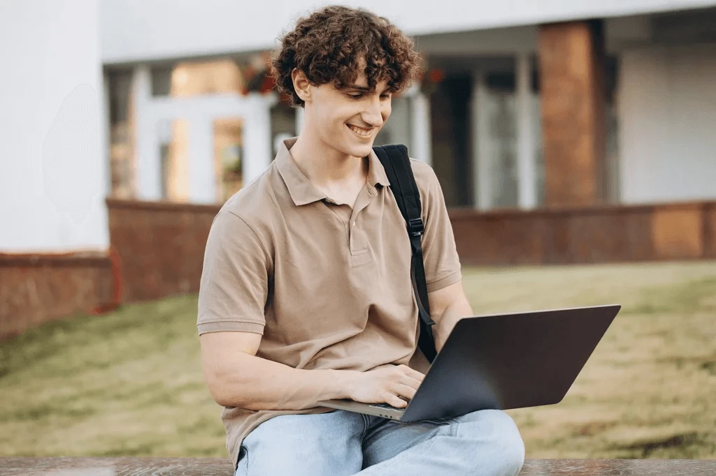 Student Updating His College Resume Using A Laptop