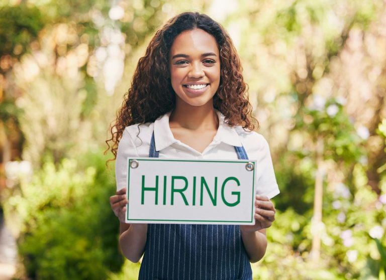 Shot of a florist holding a sign looking for new skill base hires.