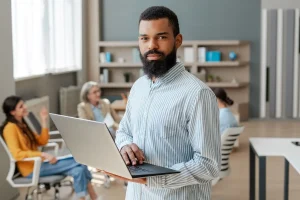 Professional Using A Laptop During A Meeting With His Colleagues