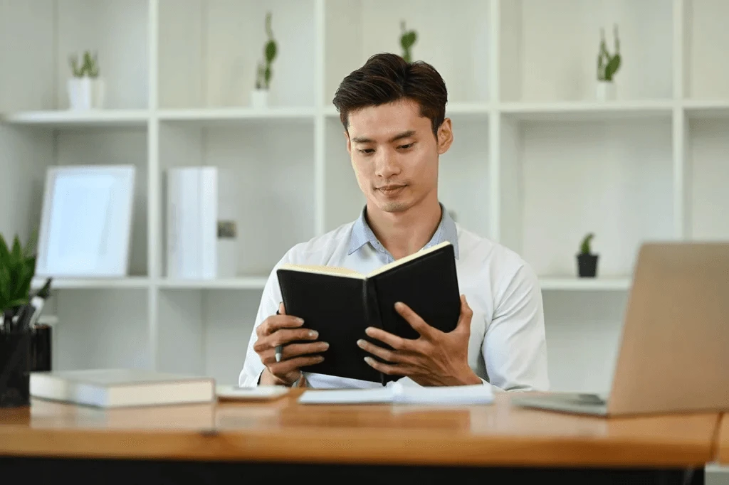 Professional Writer Reading A Book To Enhance Writing Skills