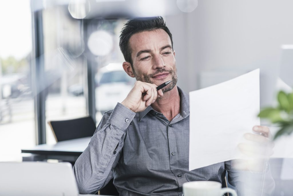 A Man Sitting In Office, Reading A Excuse Letter