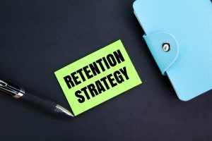 colored pen, book and paper with the word retention strategy.