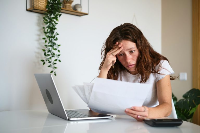 Worried woman reading problematic bills at home