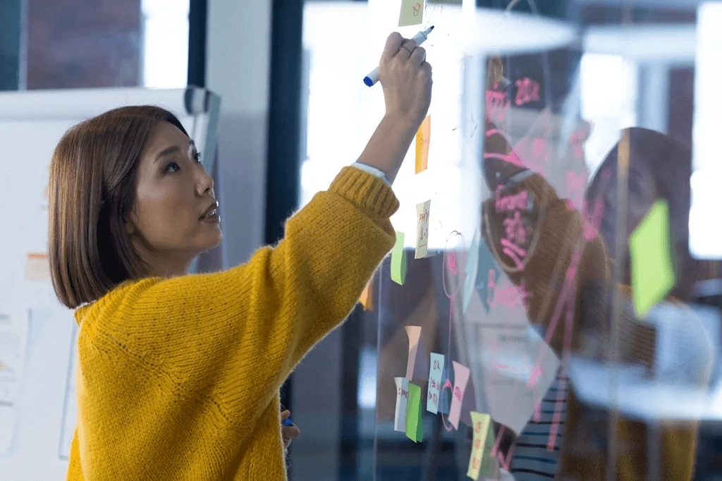 Businesswoman Writing Short-Term Career Goals On A Glass Wall