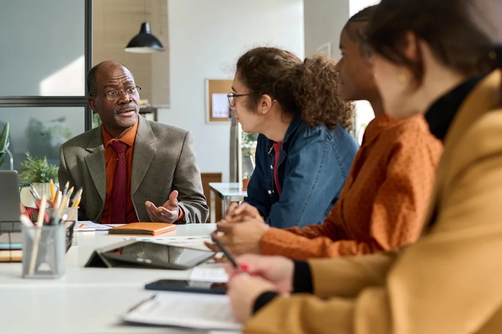 Group Of Young Professionals Asking For Career Advice From A Senior-Level Employee