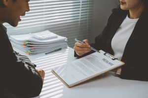 Human Resources Manager Pointing At Resume With Pen And Discussing With Candidate During Job Intervi