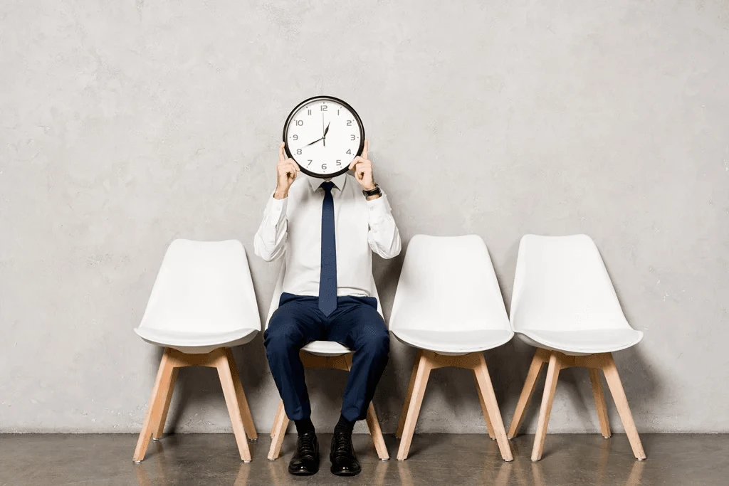 Professional Holding A Clock In Front Of Their Face, Symbolizing The Best Times To Apply For Jobs