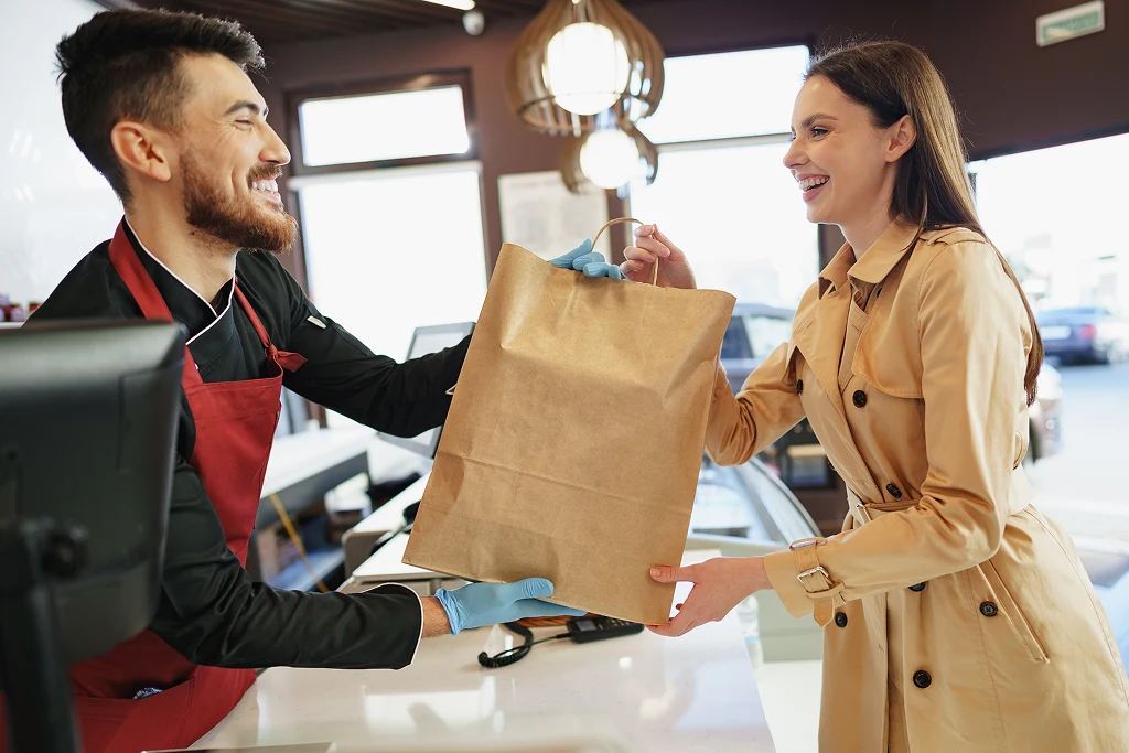 Cashier Handling Shopping Bag To Female Customer