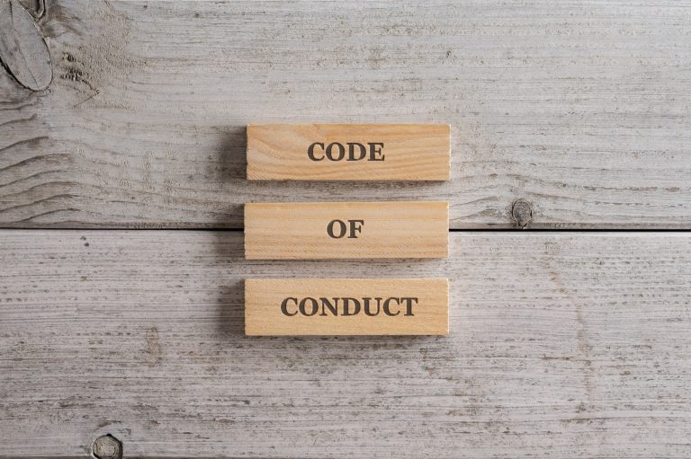 Code of conduct sign spelled on a stack of three wooden blocks