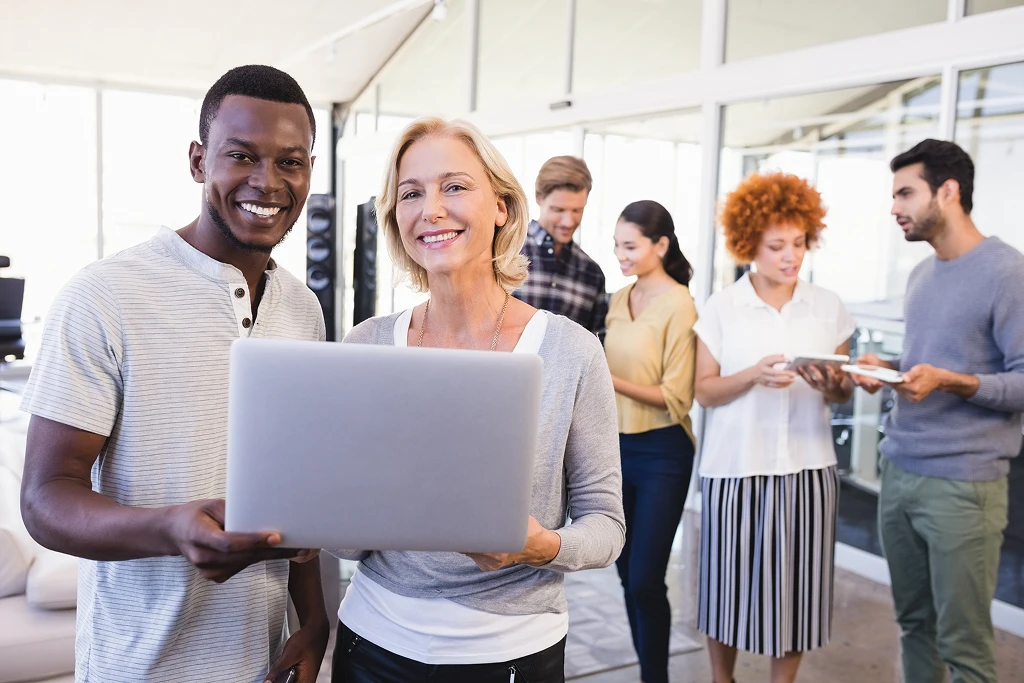 Portrait Of Smiling Business People Holding Laptop