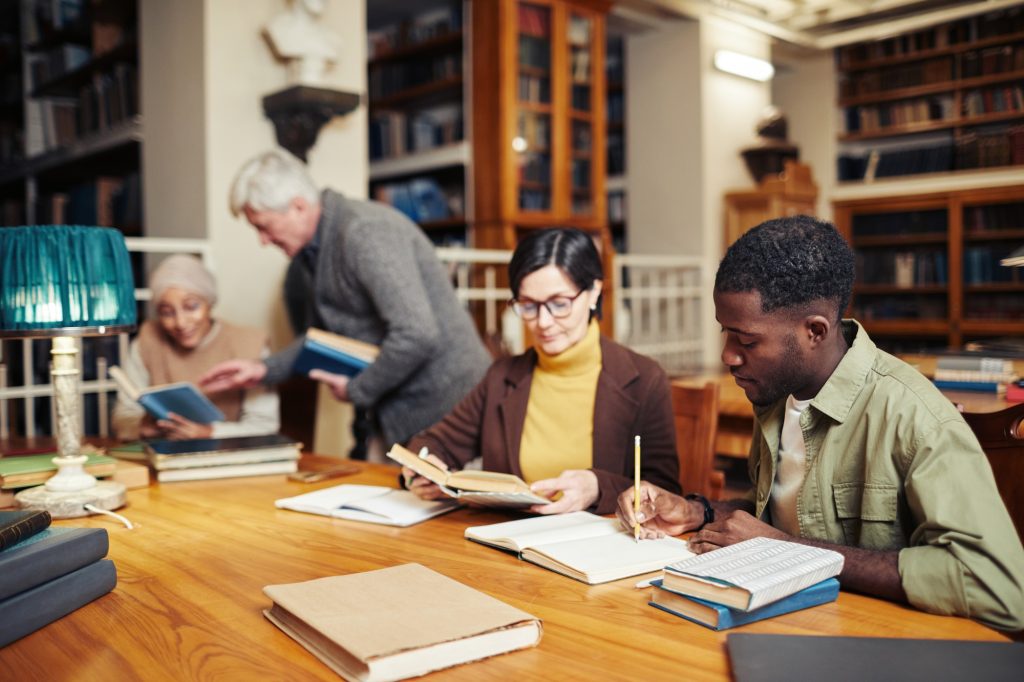 Diverse People In Library, A Diverse Group Of Library Patrons Exploring Library Resources.